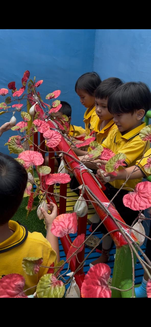 Anak-anak mengamati tanaman berdaun merah di taman sekolah