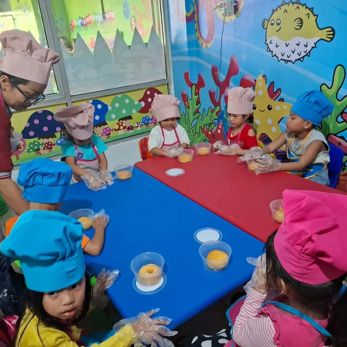 Murid mengenakan topi koki membuat kue dalam cooking class